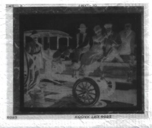 Untitled-negative of 4 men and one woman witting on a truck bed.