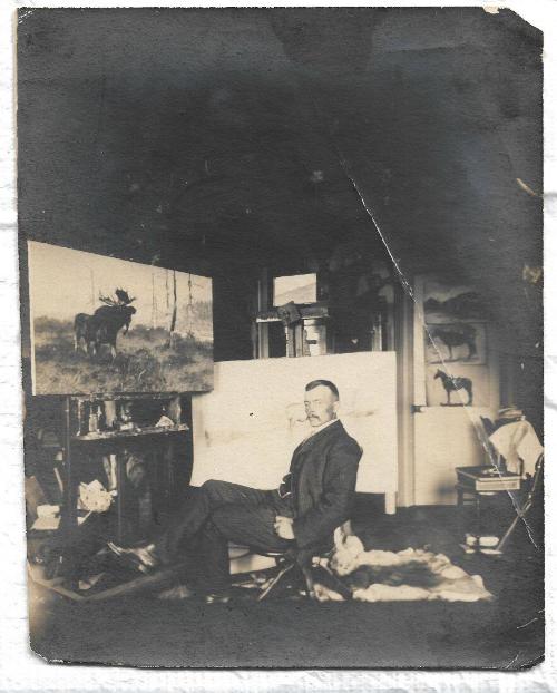 B&W photo of Rungius seated in his studio in front of several works in progress